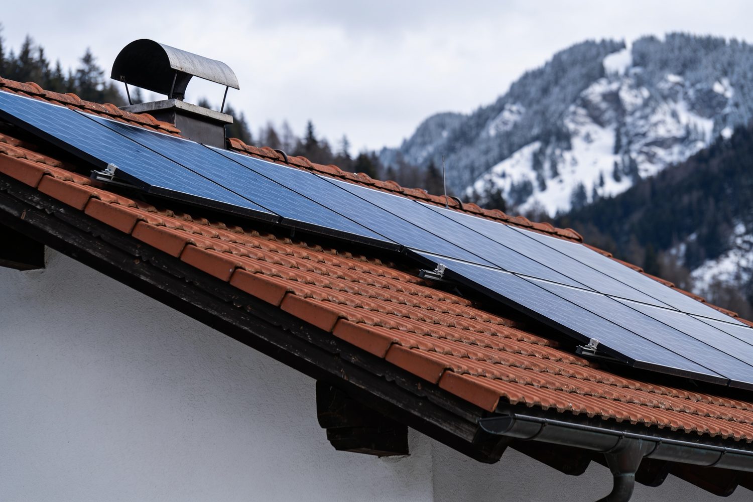 Photovoltaikmodule auf einem Ziegeldach vor Bergkulisse