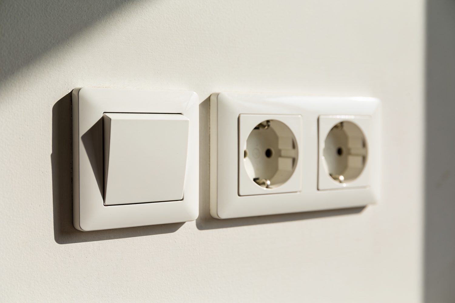 Lichtschalter und Doppelsteckdose an heller Wand